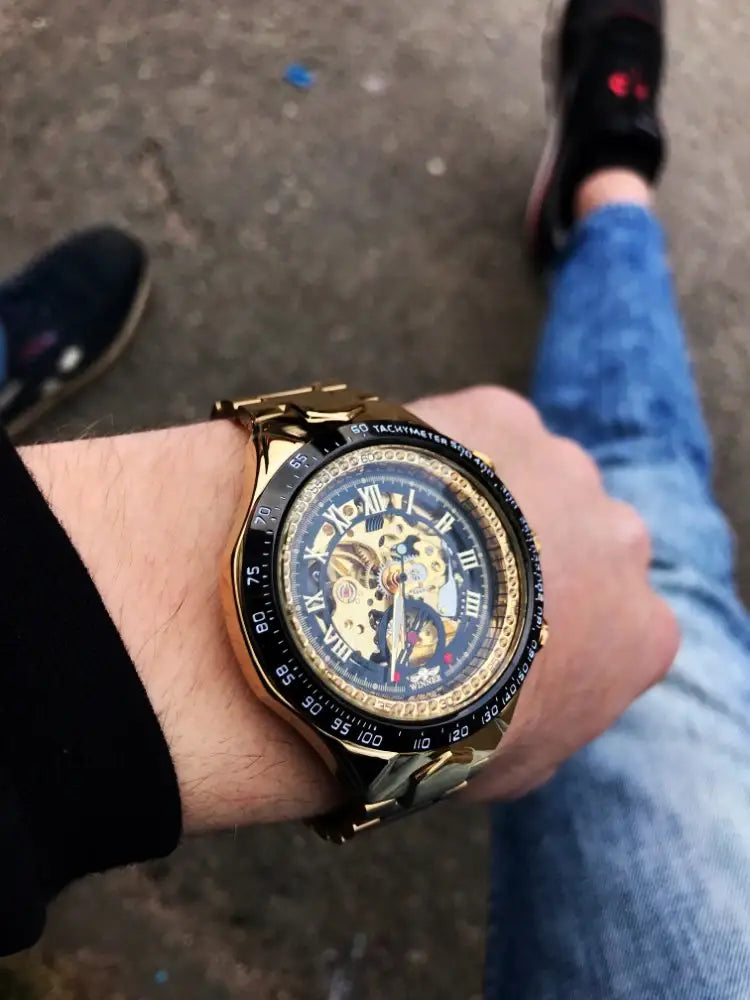 Gold-toned Winner Mechanical Sport skeleton watch with black dial and Roman numerals